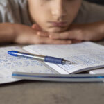A child looking down at a testing booklet. Psychoeducational testing could be what your child needs. Contact us today.