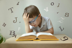 A young boy reading a book with his hand on his forehead. Representing how learning disability testing in San Francisco & Berkeley, CA can benefit your children's academic and personal life! Call today.