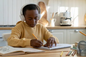A young boy with headphones on working hard on his homework. There are different locations for ADHD testing in San Francisco & Berkeley, CA. Learn more from our psychologists here. 