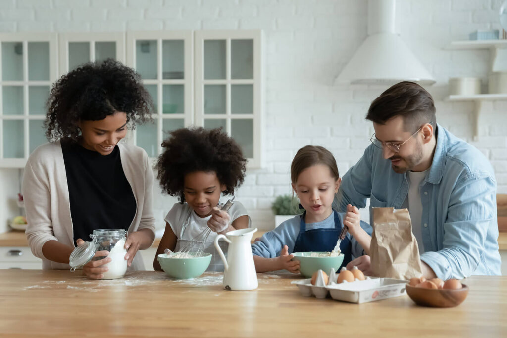 A biracial family cooking together in the kitchen sharing smiles. To help better support & advocate for your children, learn about our ADHD testing services in San Francisco, CA. We also offer ADHD & Dyslexia testing in Berkeley, CA!