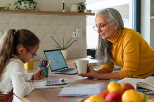 An older adult woman at the counter helping a young girl with homework. Discover how learning disability testing in Berkeley, CA can help your child thrive. Learn more about learning disability testing here.