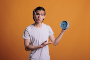 A young adult holding a blue clock with a questionable expression. Discover the benefits of neuropsychological evaluations in San Francisco, CA. We also have IQ testing in two locations!
